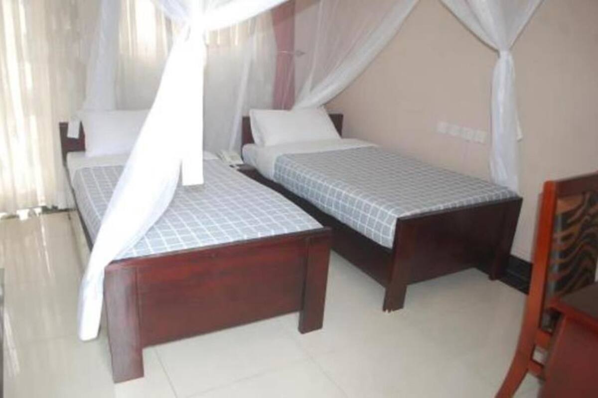 A bedroom with two single beds, each with a canopy bedspread and white pillows.