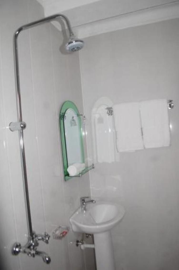 A bathroom with a shower, a sink, a mirror, and a towel rack.