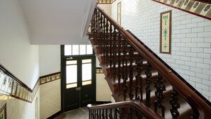 A staircase with ornate wooden railings and white tiled walls. - Nairn Apartment - West End close to University (Glasgow)