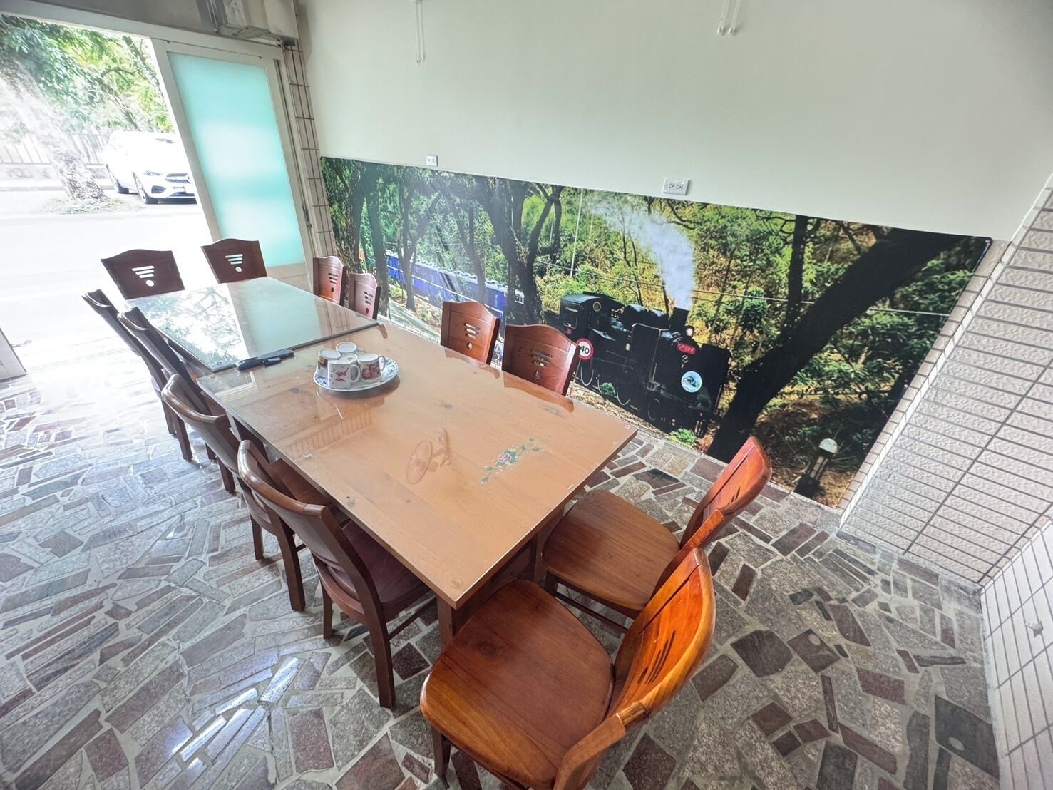 A dining area with a wooden table and chairs, a tiled floor, and a mural of a train on the wall.