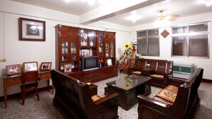 A living room with a wooden cabinet, a television, and a sofa. - Plum Inn 1 (Jiji)
