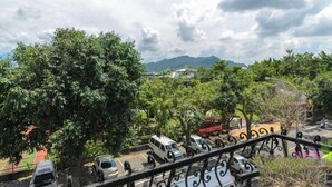 A view of a parking area with several vehicles, trees, and a mountainous landscape in the background. - Plum Inn 1 (Jiji)