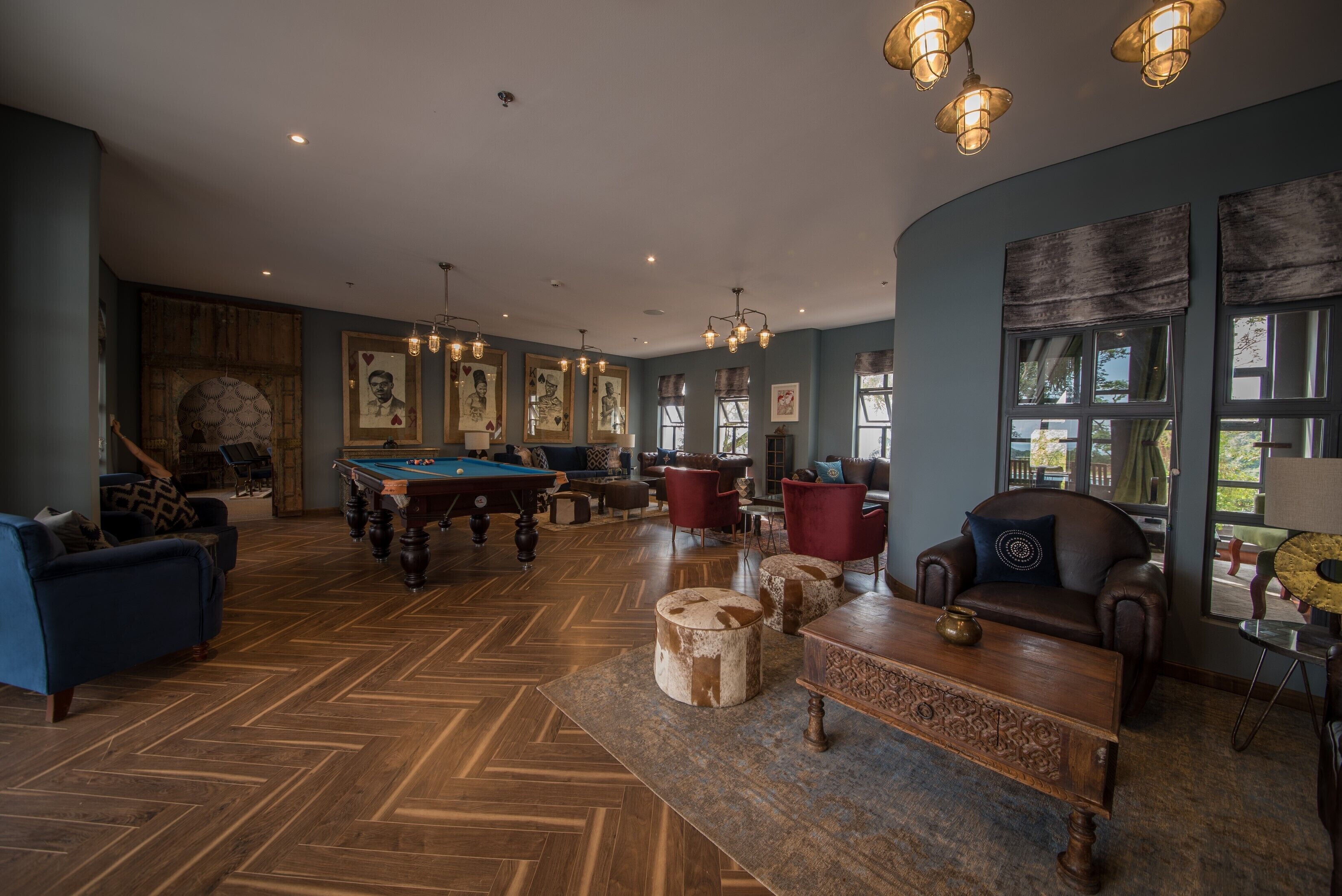 A spacious room with a pool table, comfortable seating, and large windows.