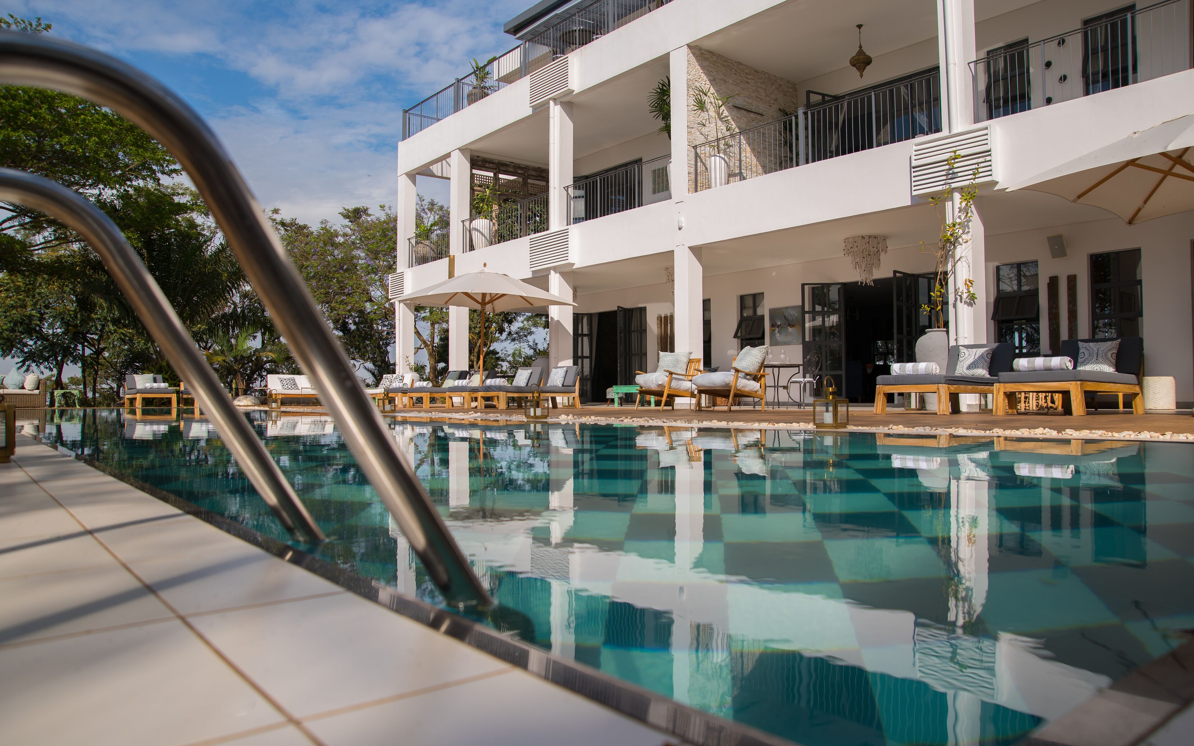 Un hotel moderno con piscina, zona de estar exterior y estructura de varios pisos.