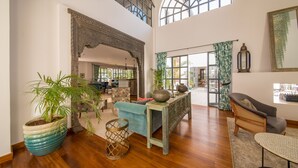 A spacious living area with a high ceiling, a large window, and a view of the outdoors. - Latitude 0 Degrees (Kampala)