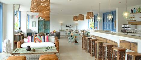 A spacious living area with a large sofa, ottomans, and a dining table set for a meal.