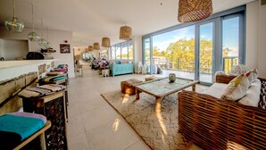 A spacious living area with a large window, wicker furniture, and hanging light fixtures. - Latitude 0 Degrees (Kampala)