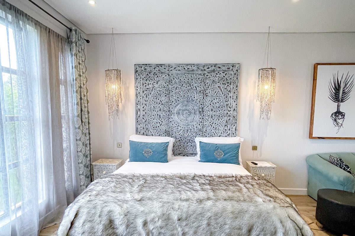 A modern bedroom with a large bed, patterned headboard, and a geometric floor design.
