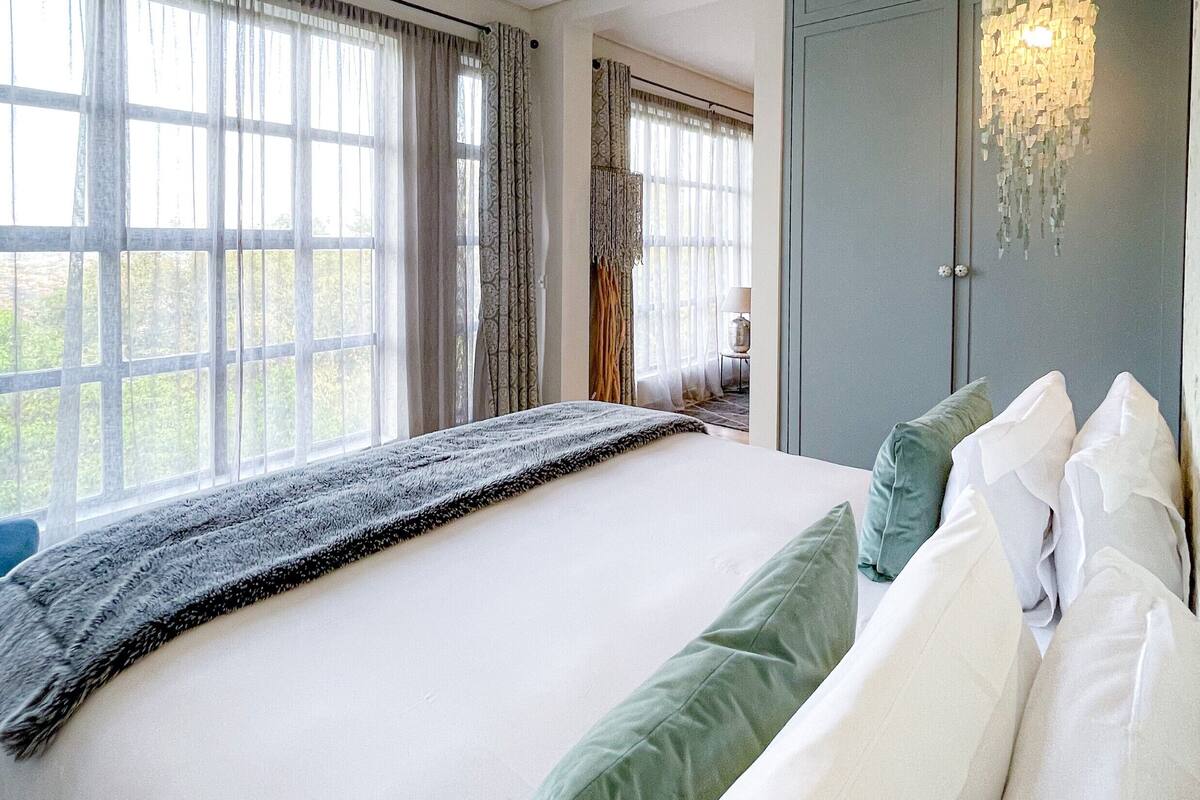 A spacious bedroom with a large bed, a wardrobe, and a chandelier.