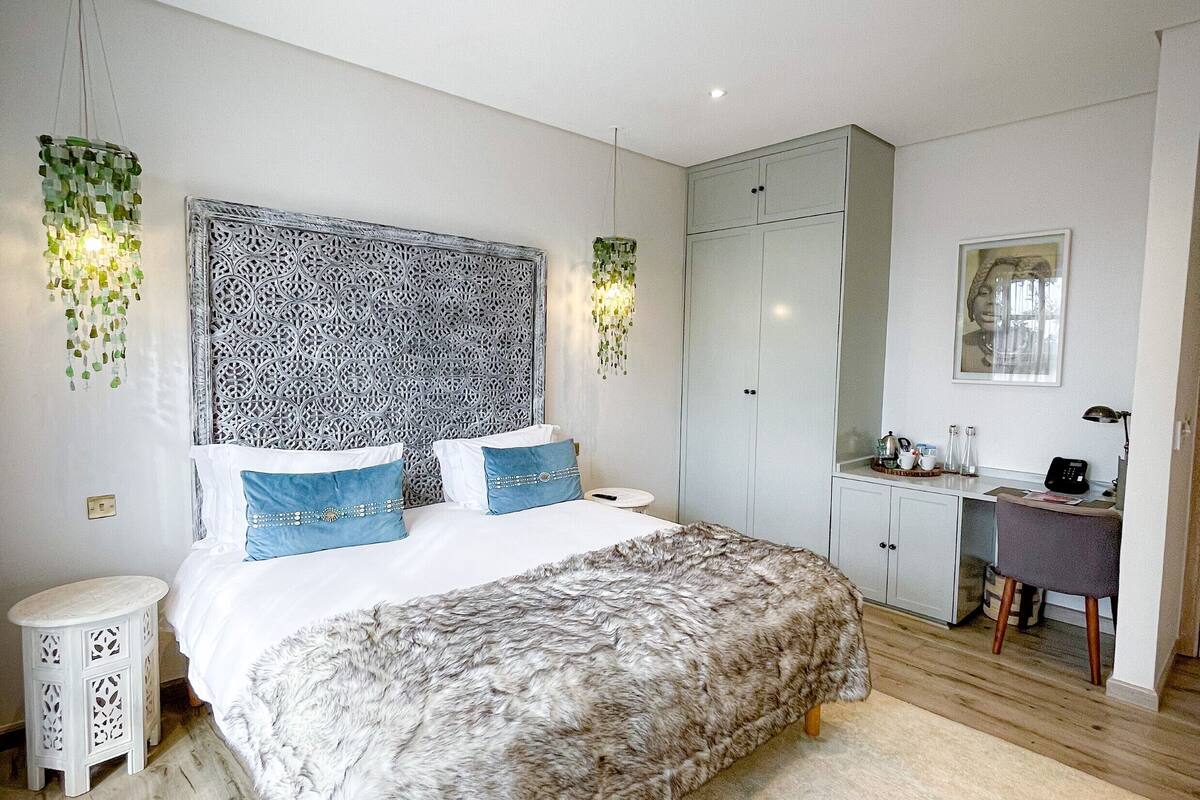 A modern bedroom with a large bed, a desk, and a wardrobe.