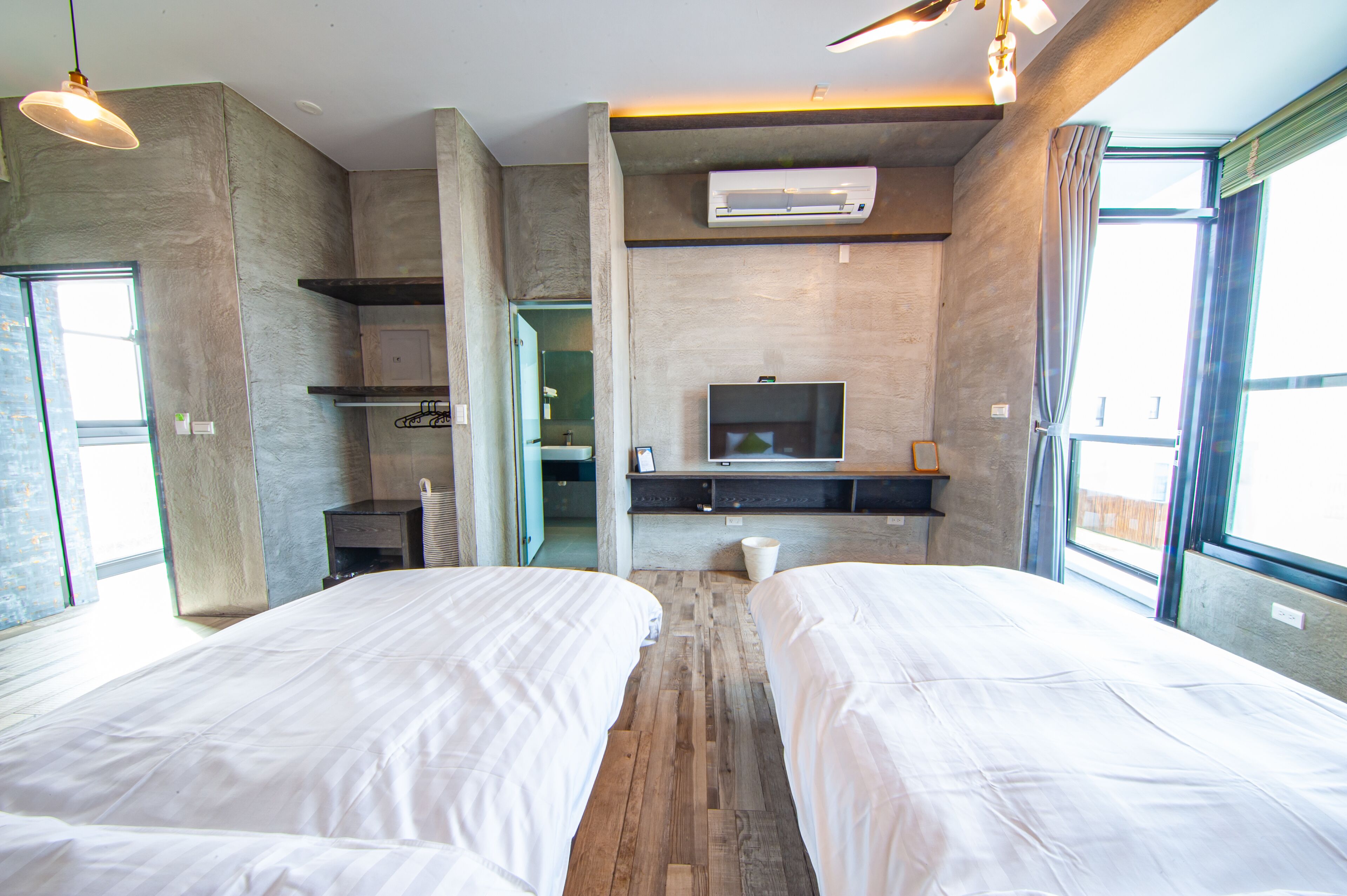 A modern hotel room with two beds, a TV, and a large window.