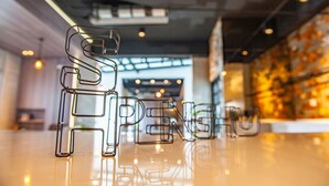 Un interior moderno con suelo reflectante y estructuras de letras metálicas que deletrean 'SPREE'.