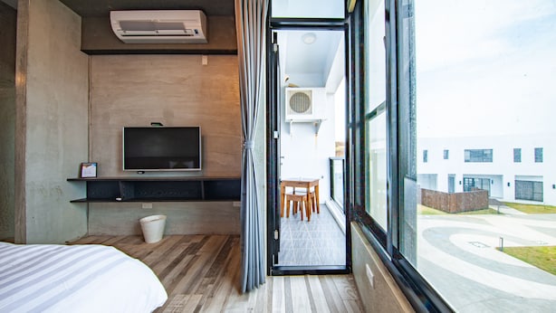 Una habitación de hotel con una cama, televisión, una mesita y ventana con vistas al exterior.