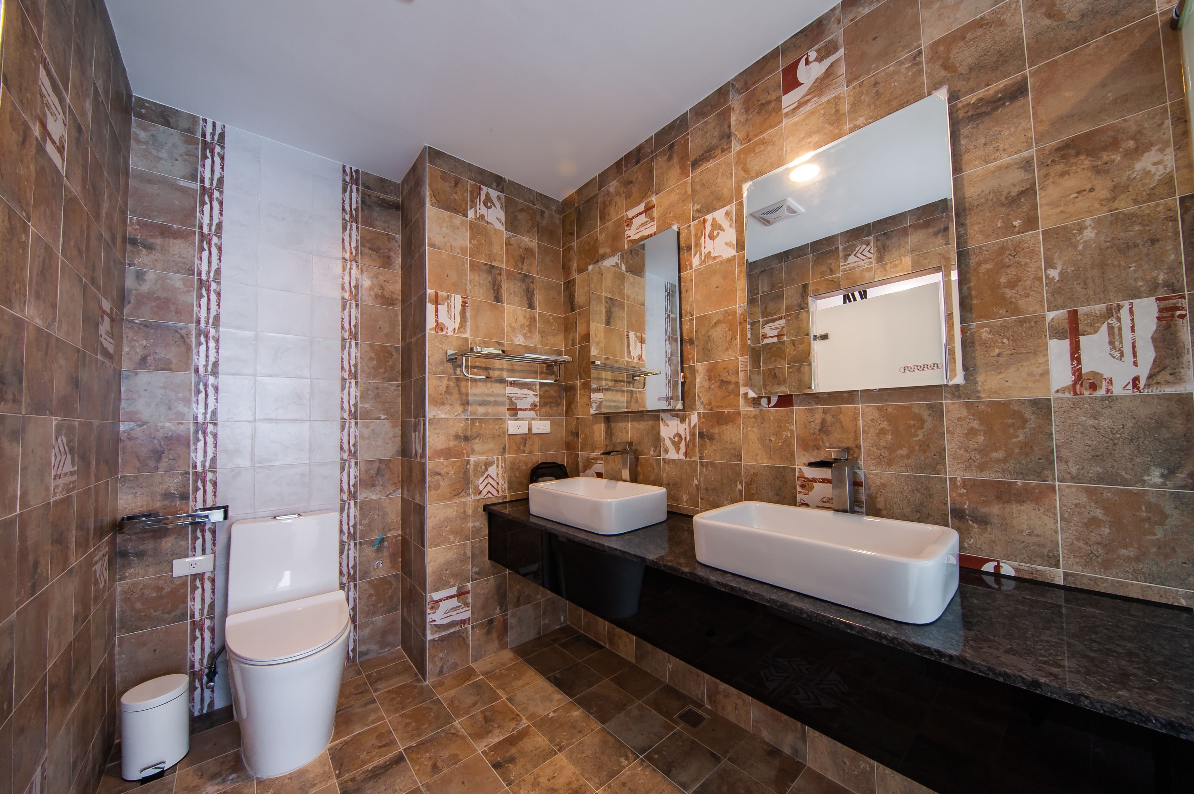A modern bathroom with two sinks, a toilet, and a shower.
