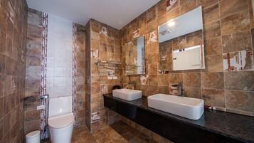A modern bathroom with two sinks, a toilet, and a shower.