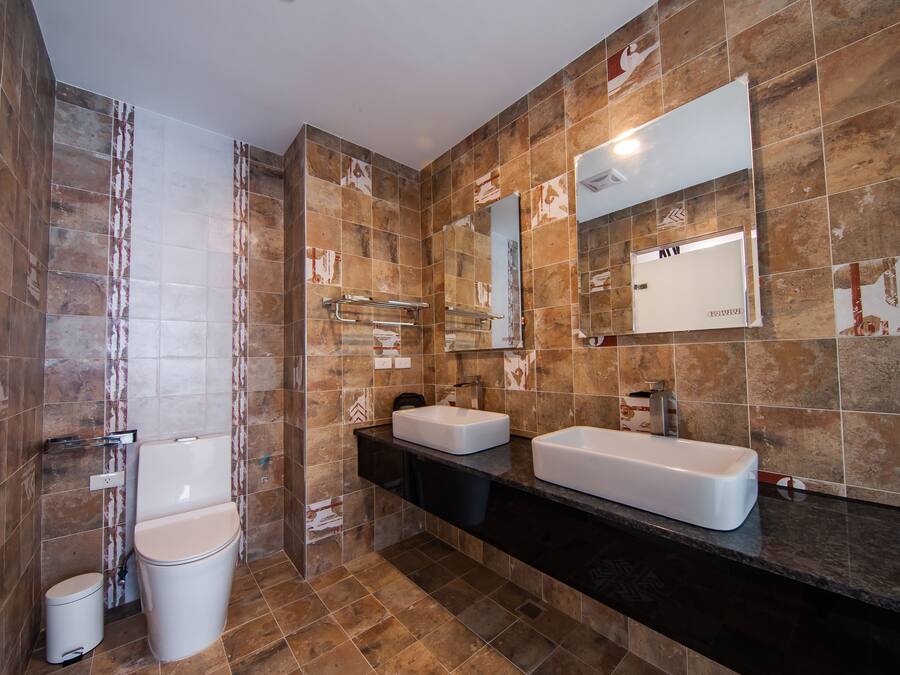 A modern bathroom with two sinks, a toilet, and a shower.