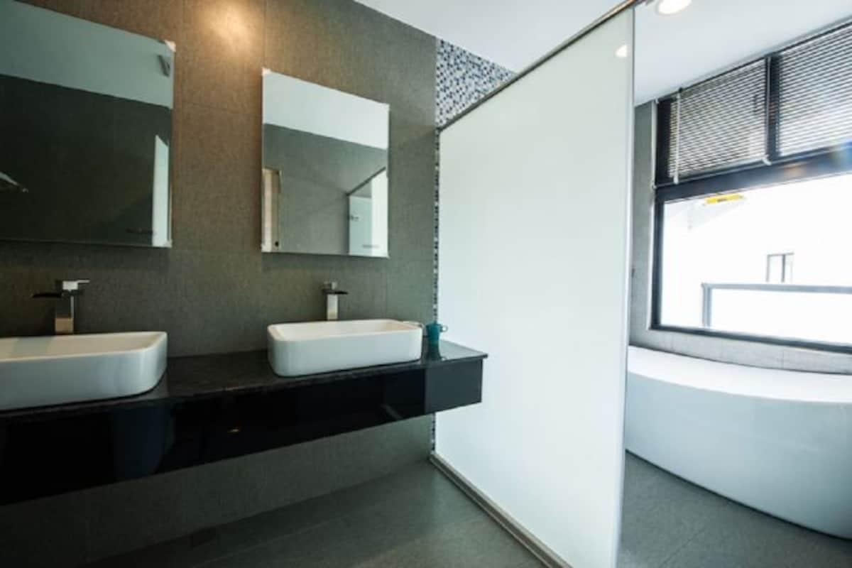Un baño moderno con dos lavamanos, un espejo grande y una ventana.