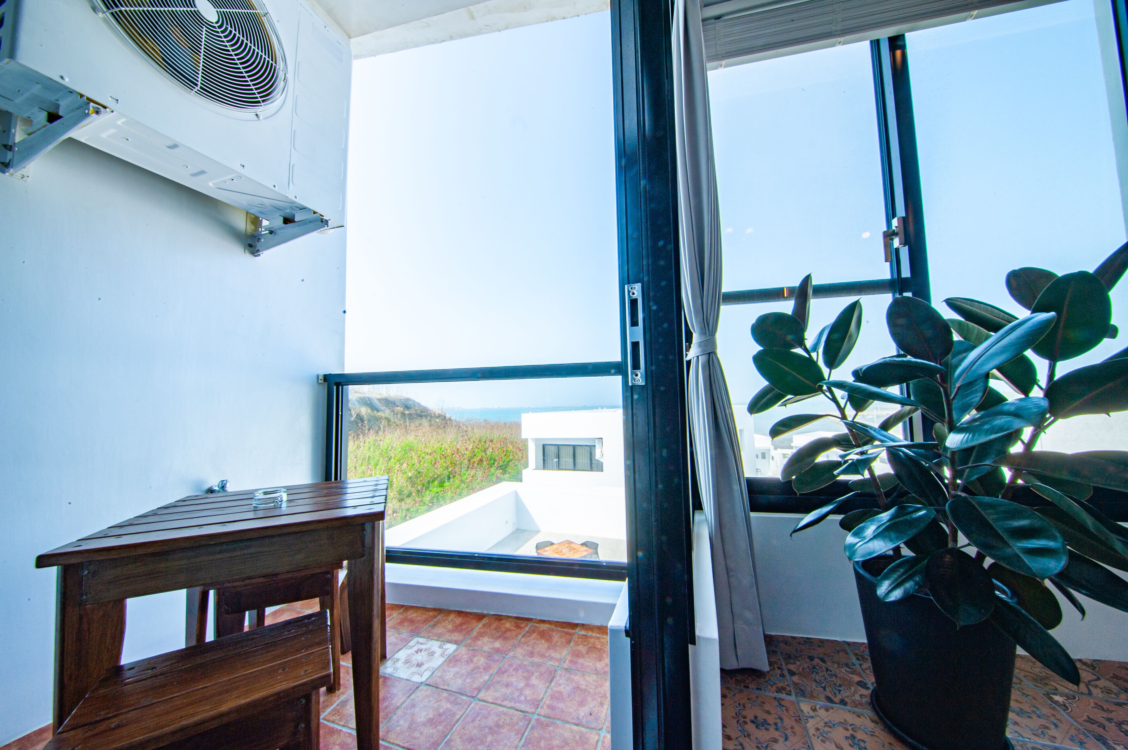 Un balcon avec une table en bois, un pot de fleurs et une vue sur la mer.