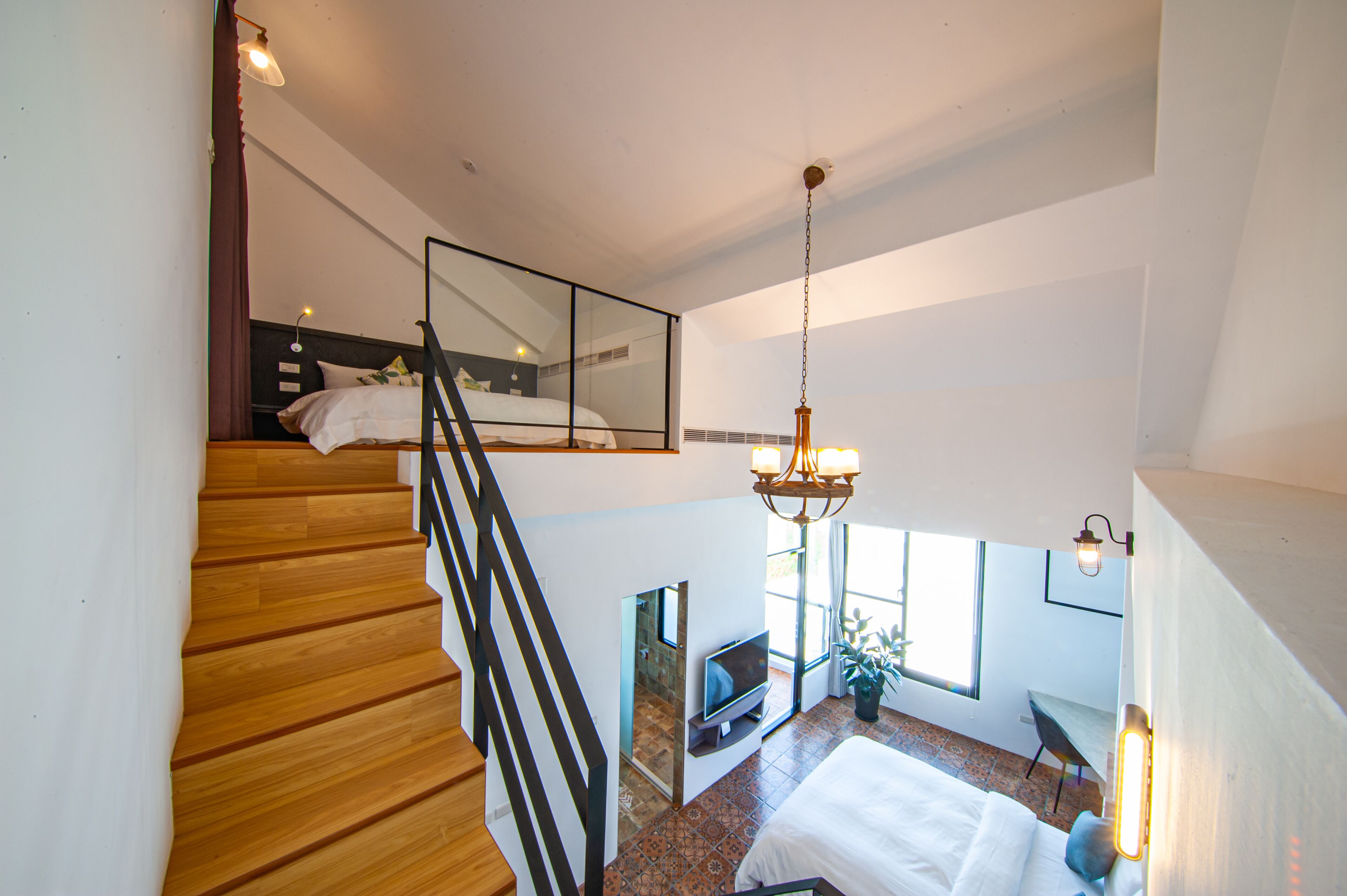 Ein Schlafzimmer mit Bett, Fernseher, Blumentopf und Treppe.