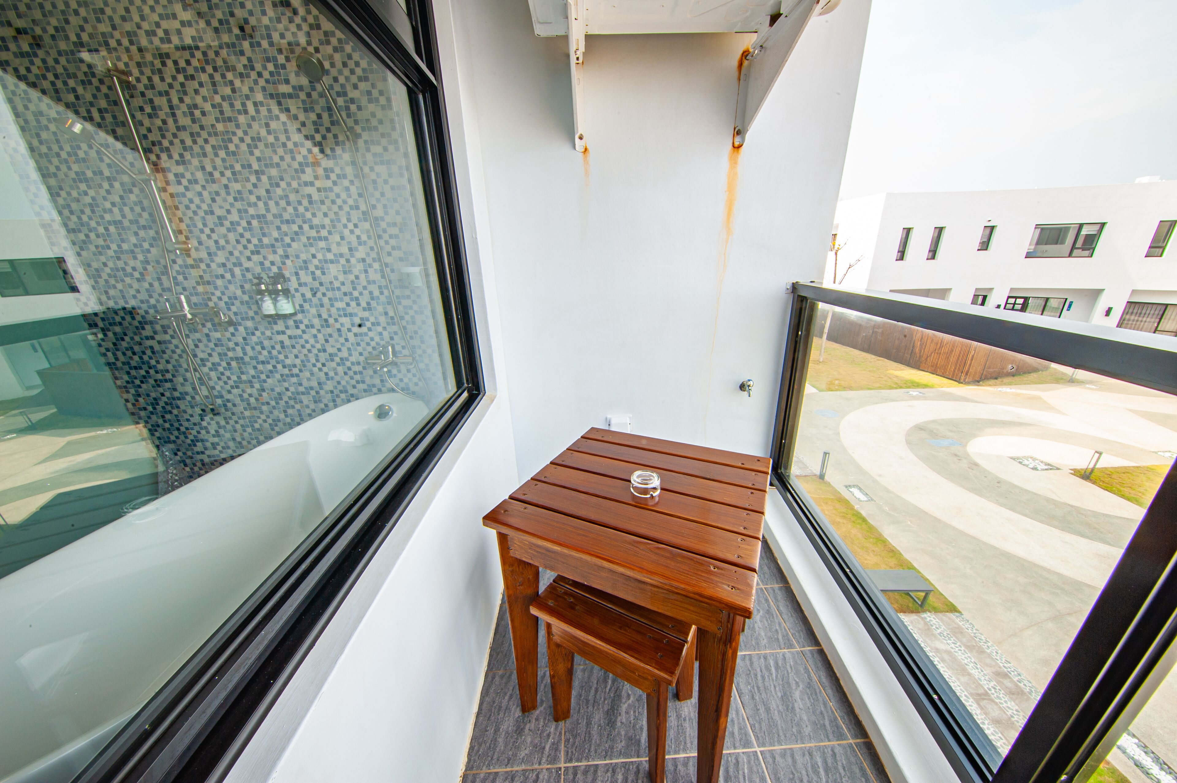 En balkon med et træbord og udsigt til en moderne bygning.