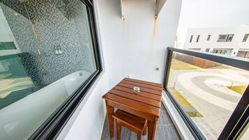En balkon med et træbord og udsigt til en moderne bygning.