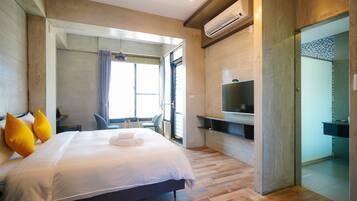 A modern hotel room with a large bed, a TV, and a bathroom visible through an open door.