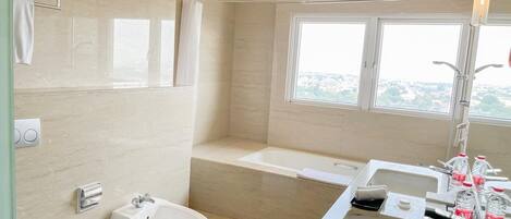 A modern bathroom with a bidet, toilet, bathtub, and sink.