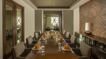 A conference room with a long table set for a meeting, surrounded by chairs, and a decorative wall panel.