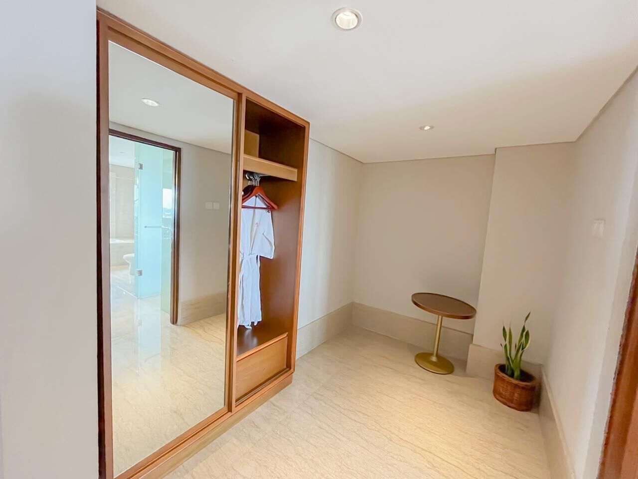 A modern room with a large mirror, a small round table, and a potted plant.