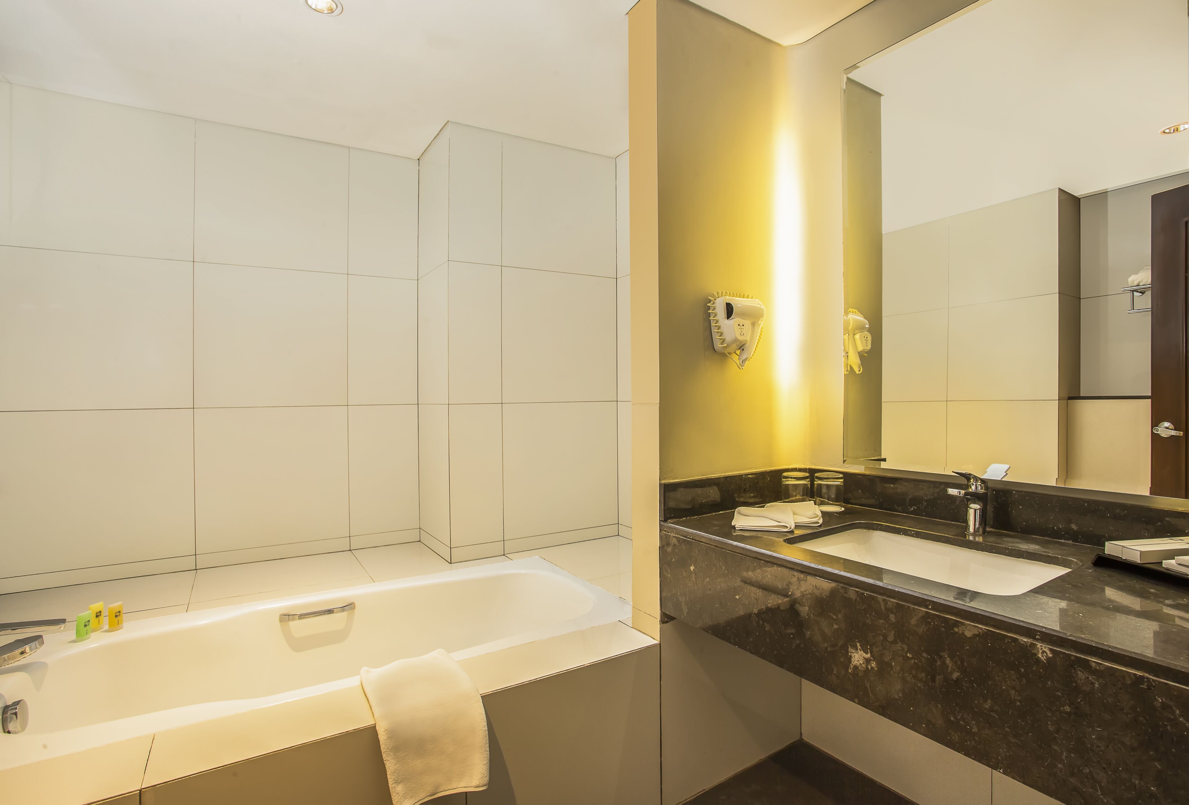 A modern bathroom with a bathtub, two sinks, and a large mirror.