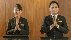 Two individuals in business attire standing at a reception desk with a wooden panel background. - Swiss-Belhotel Bogor (Bogor)