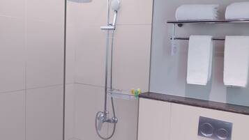 A modern shower with a glass door, a towel rack with two towels, and a control panel on the wall.