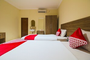 Une chambre d’hôtel avec deux lits, une armoire en bois, un miroir et un lavabo.