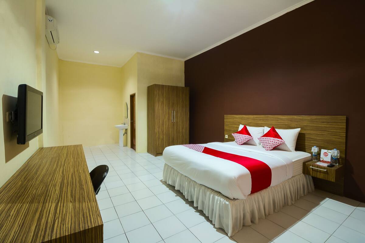 Ein Hotelzimmer mit Bett, Schreibtisch, Fernseher und Kleiderschrank.
