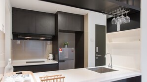 A modern kitchen with dark cabinetry, a stainless steel sink, and a wine rack. - Boulevard Residence (Petaling Jaya)