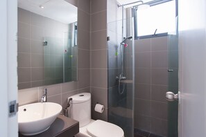 Un baño moderno con lavamanos, inodoro y ducha.