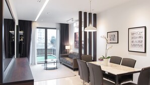 A modern living room with a sofa, a dining table with chairs, a TV, and a balcony with curtains. - Boulevard Residence (Petaling Jaya)
