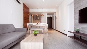 A modern living room with a grey sofa, a wooden coffee table, and a dining area with a white table and chairs. - Boulevard Residence (Petaling Jaya)