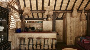 Uma cozinha rústica com teto de madeira, área de bar com banquetas e luminária de teto em tear.