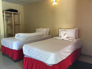 Two single beds with red skirts, white bedding, and a wooden wardrobe with hangers. - Athoma Guest House (Shakawe)