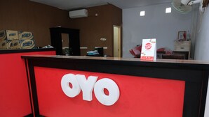 A reception desk with a red and black color scheme, a large 'OYO' sign, and a signboard with promotional text. - Hotel O Mars Kost Syariah (Jambi)