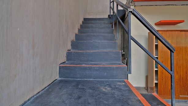 A staircase with black steps and orange edges, leading to a wooden door. - Hotel O Mars Kost Syariah (Jambi)