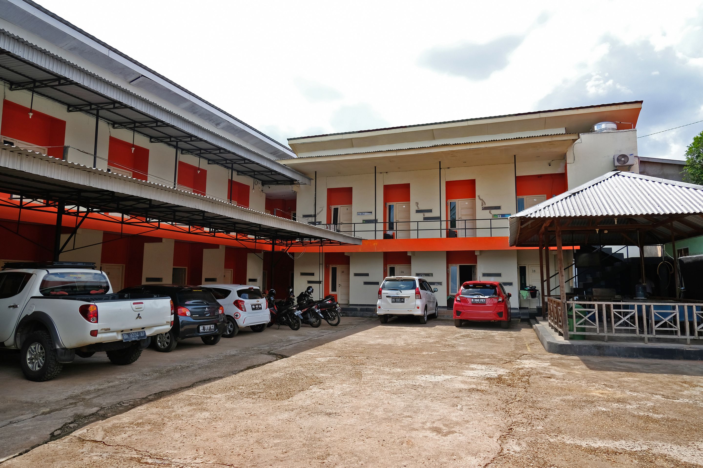 Un edificio con varios espacios de estacionamiento, un área techada y un amplio espacio abierto al frente.