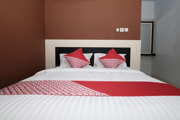 A bed with a white and red patterned bedspread, two red pillows, and a red throw blanket.