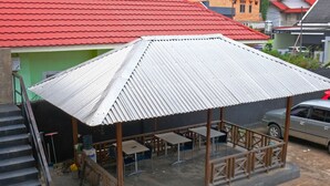 A covered outdoor seating area with tables and chairs, a staircase, and a car parked nearby. - Hotel O Mars Kost Syariah (Jambi)