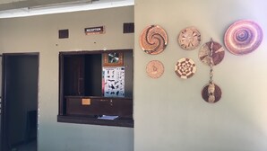 Un área de recepción con un cartel, una ventana con un póster y una pared decorada con tapices.