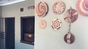 Un área de recepción con un cartel, una ventana con vistas y una pared decorada con piezas de arte circulares tejidas.