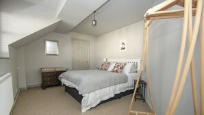 A bedroom with a bed, dresser, and a wooden ladder.