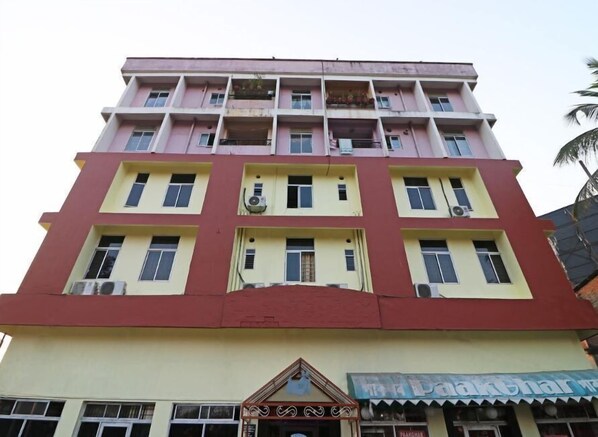 A multi-story building with a flat facade, multiple balconies, and a ground-level shop with signage. - Hotel Rhino (Guwahati)