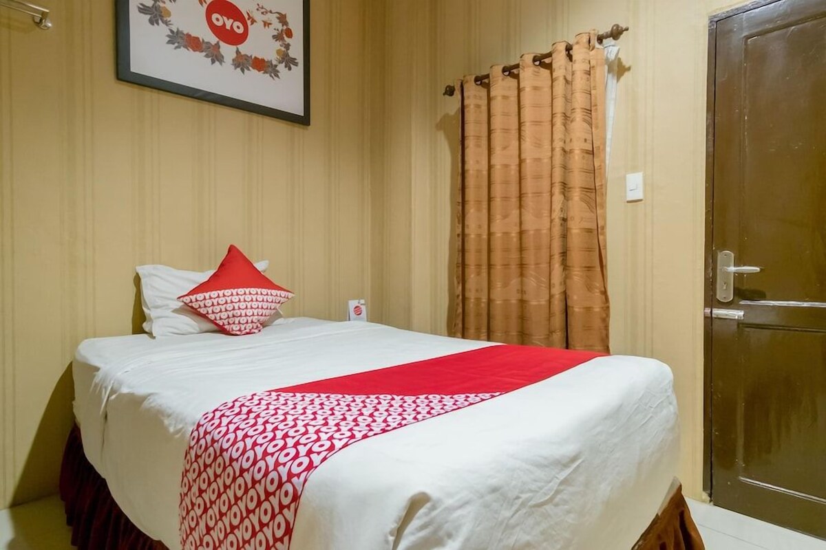 Een hotelkamer met een bed, een deur en een bordje aan de muur.